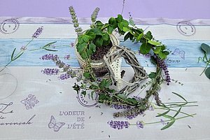 Kranz aus grünen Blättern und Lavendelzweigen auf einem Tischläufer mit floralen und französischen Schriftmotiven